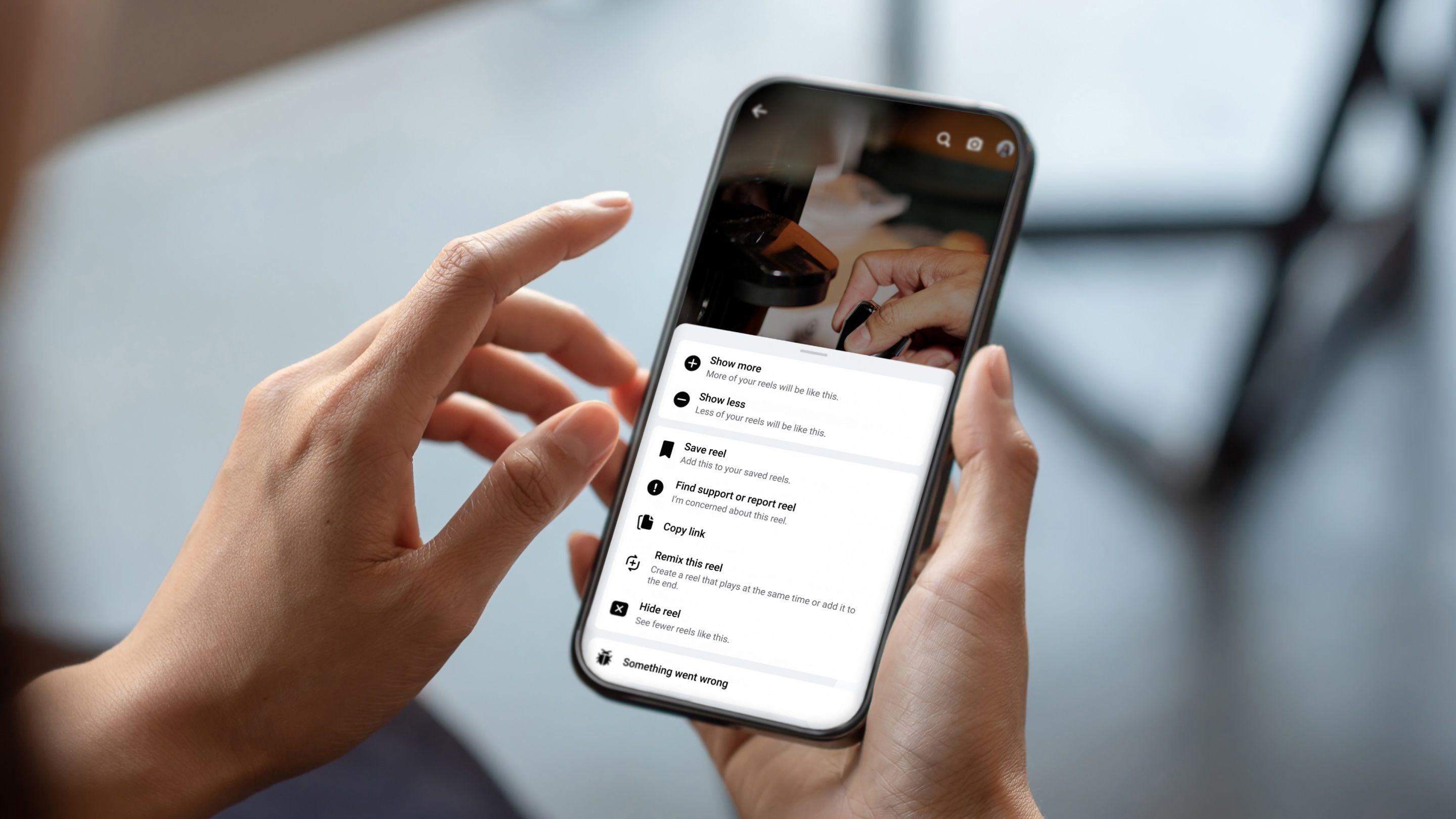 A person holding a phone with the Facebook app opened in their right hand.
