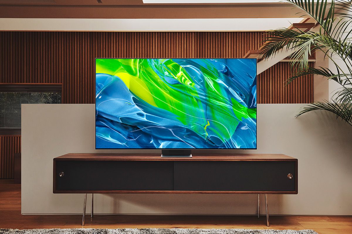 A large television sits atop a mid-century modern wood stand.