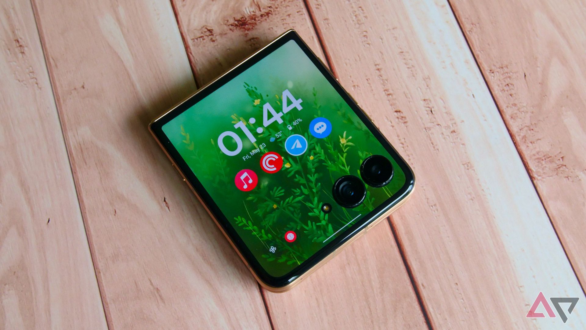 The Moto Razr Ultra with its cover display showing on a wooden backdrop.
