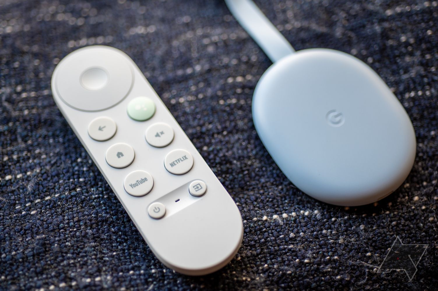 A Chromecast device next to a Google TV remote