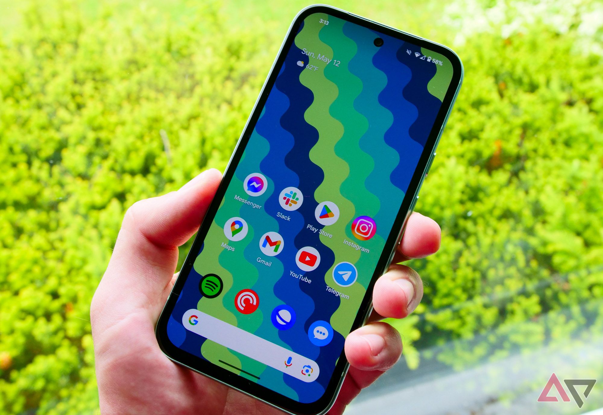 The Pixel 8a in a hand held in front of a window.