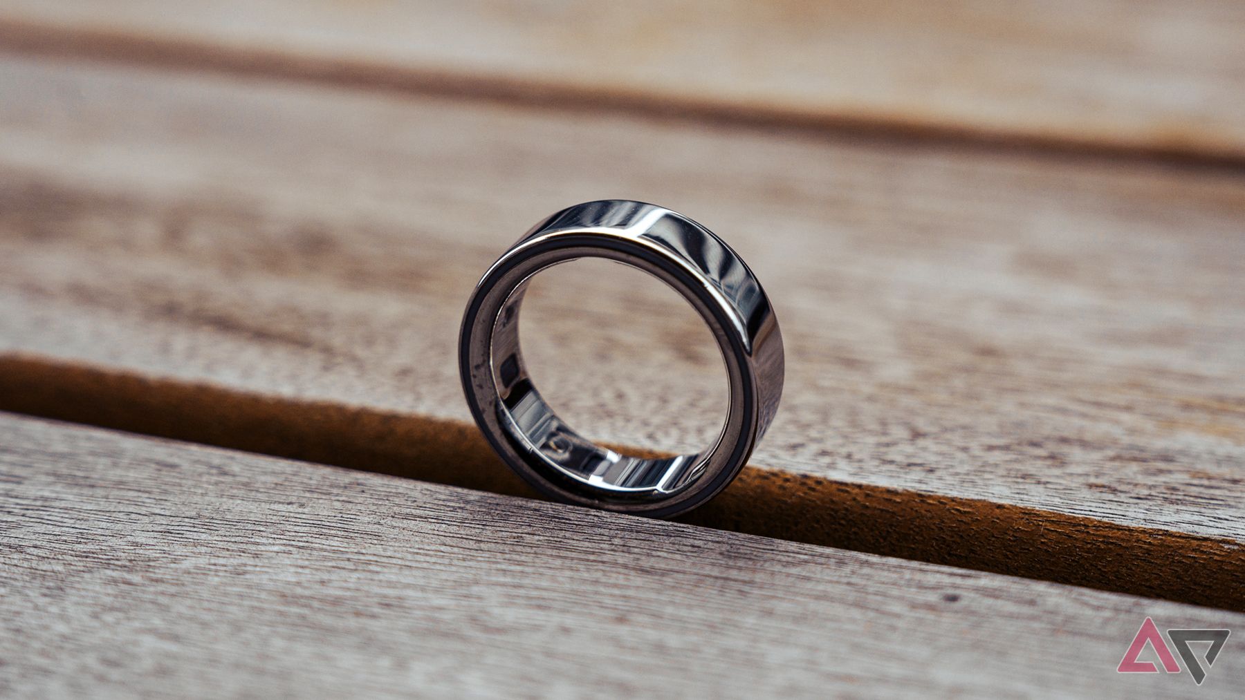 Oura Ring 4 sitting upright on its own atop a wooden table.