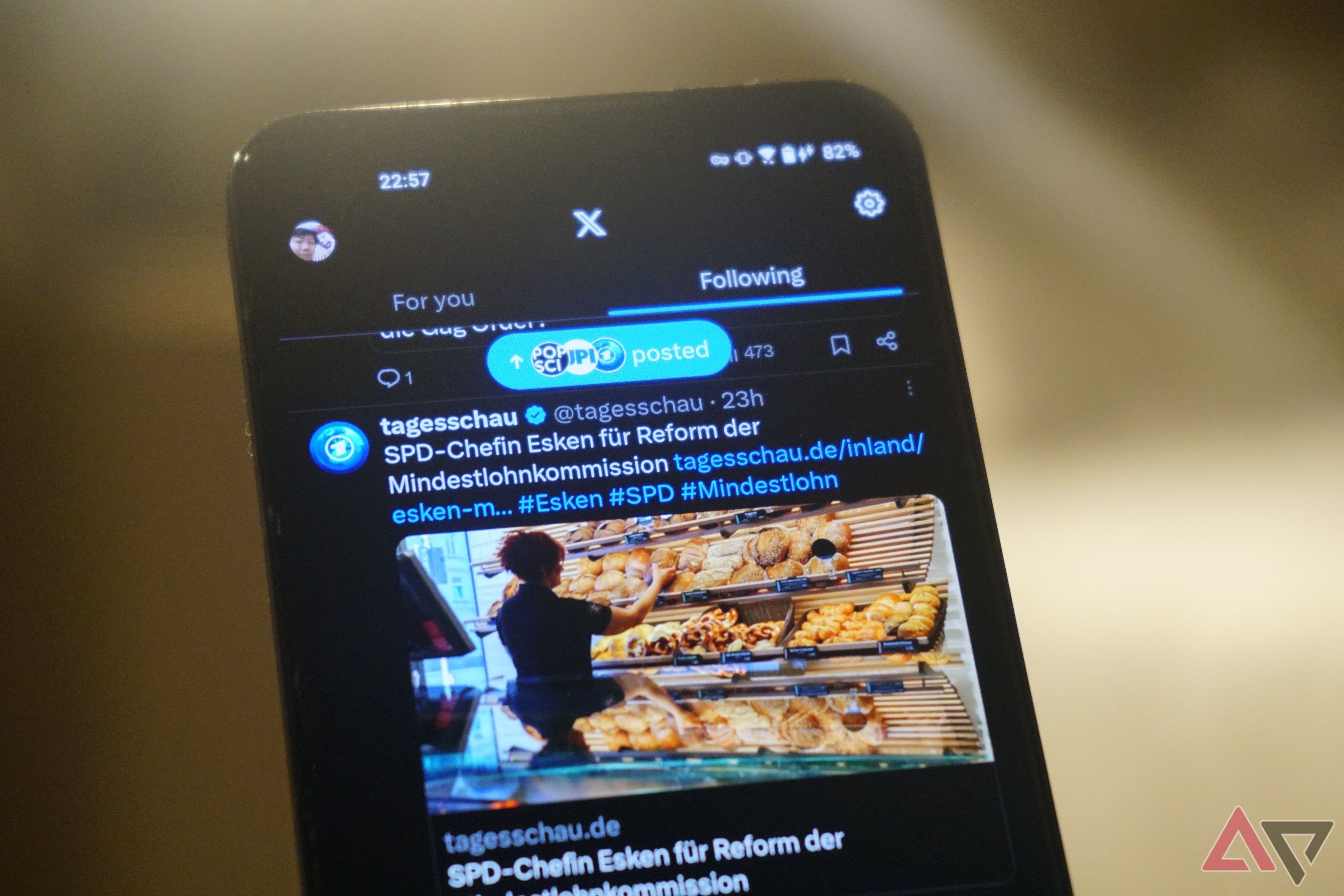 A smartphone shows the X app feed