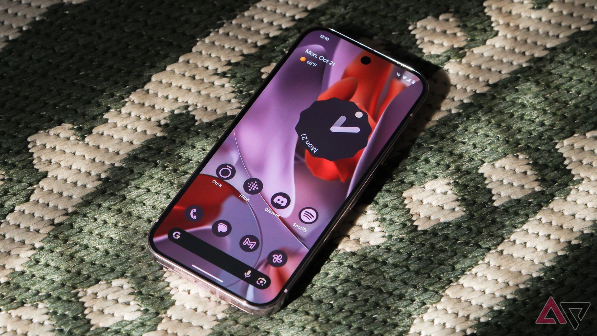 The Google Pixel 9 Pro sitting screen-up on a green rug. 