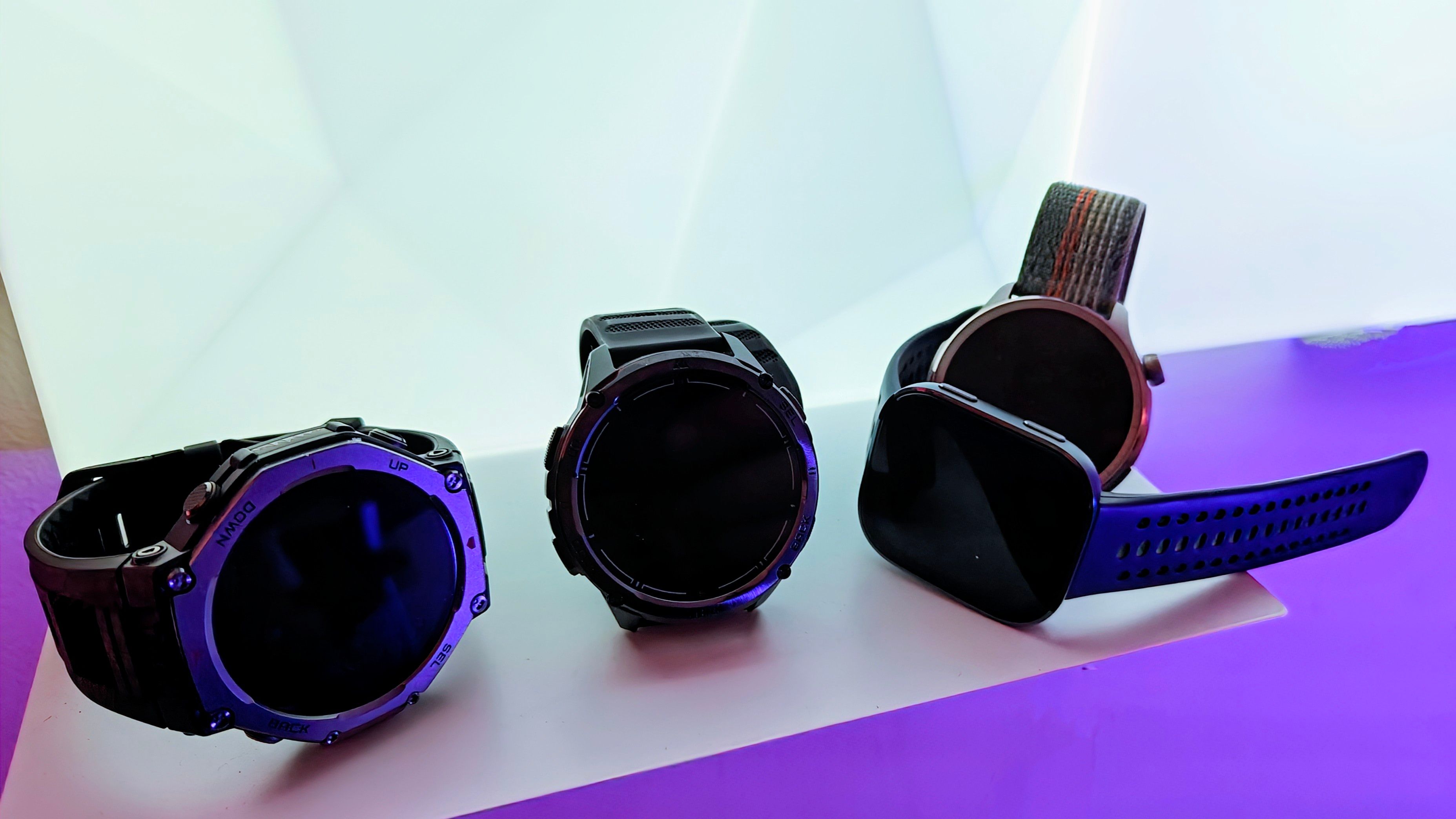 Amazfit and Kospet smartwatches on a shelf with colored lights