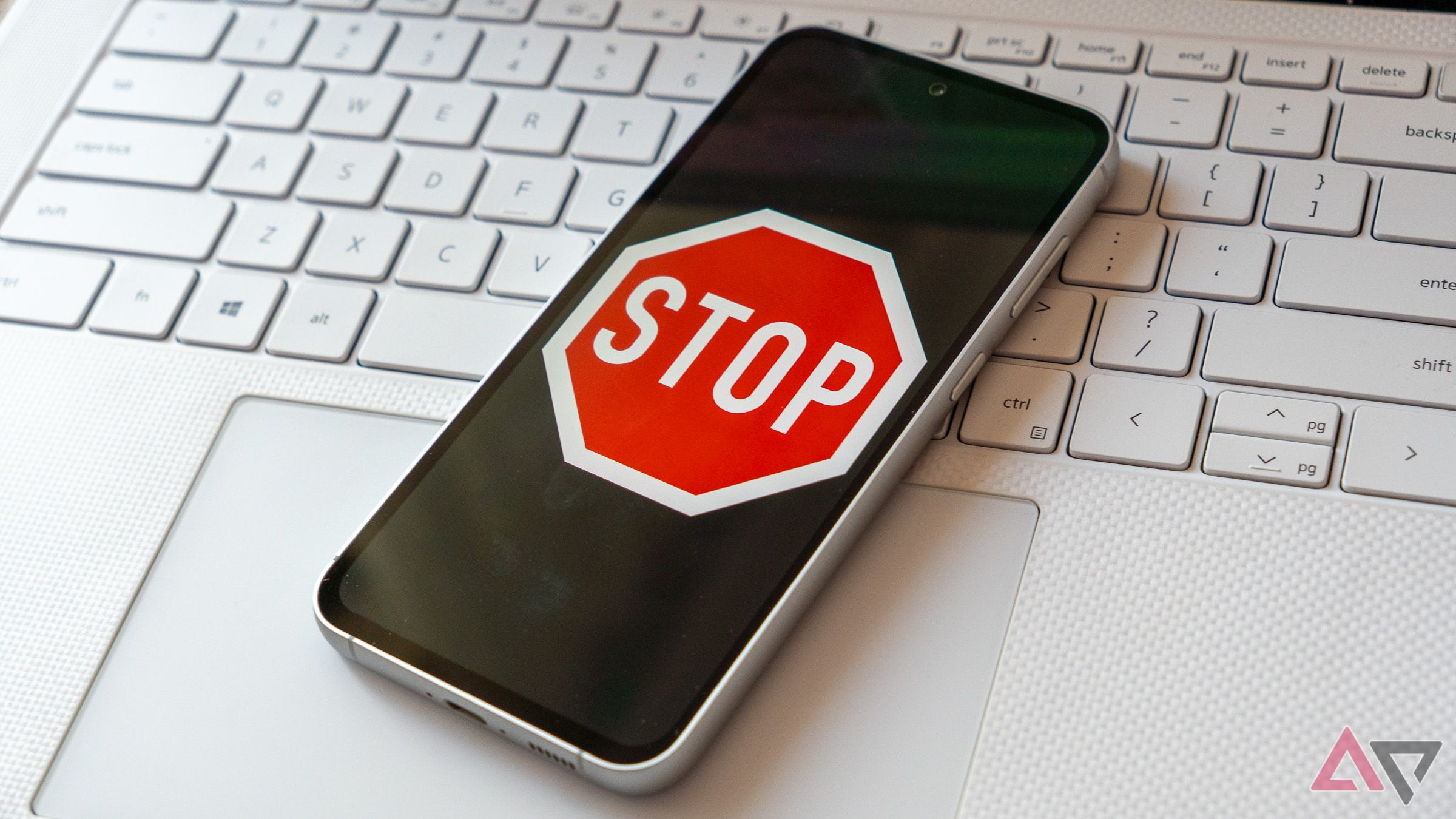 a phone displaying a stop sign on a white laptop keyboard