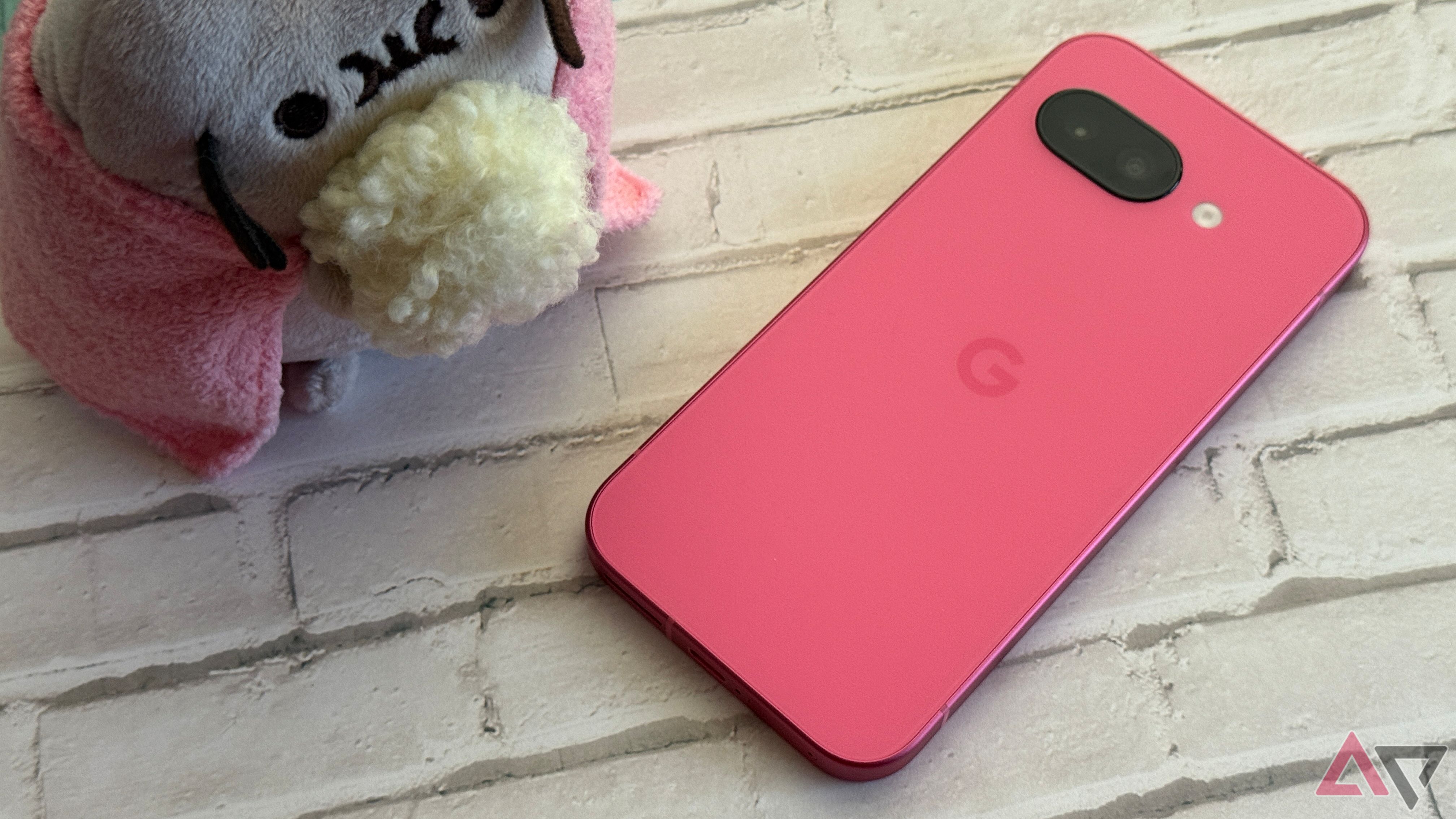 Google Pixel 9a in peony sitting next to a Pusheen with popcorn