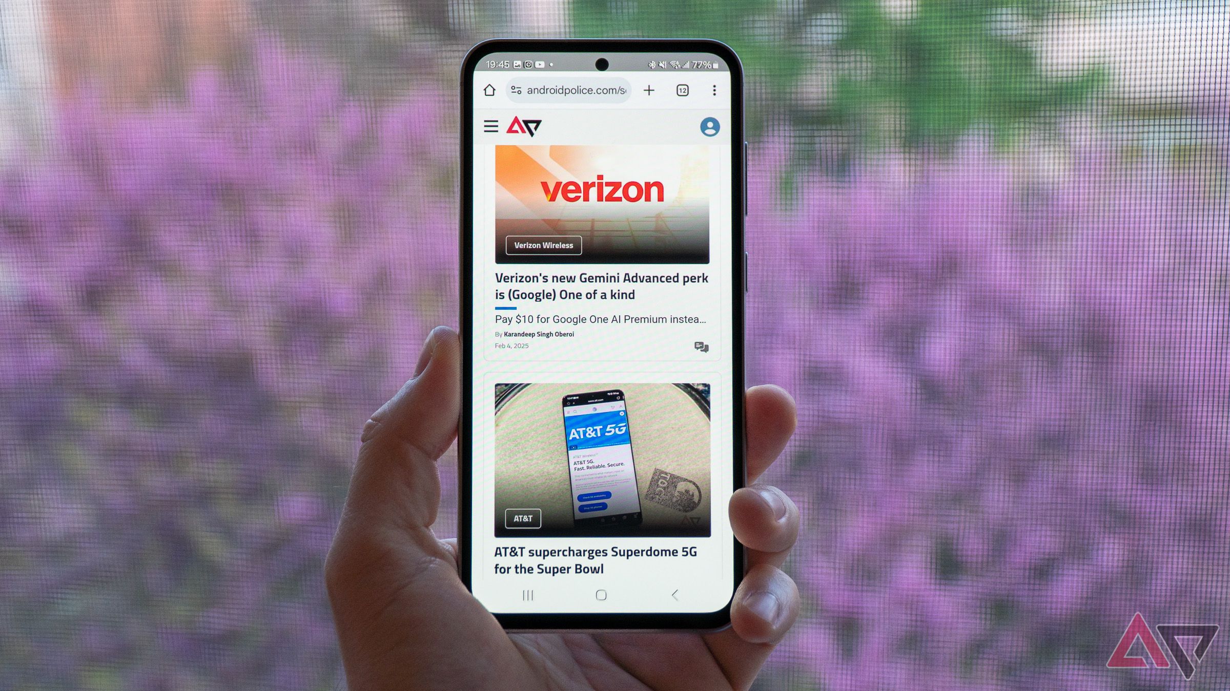 a phone in hand displaying a web page against a pink background