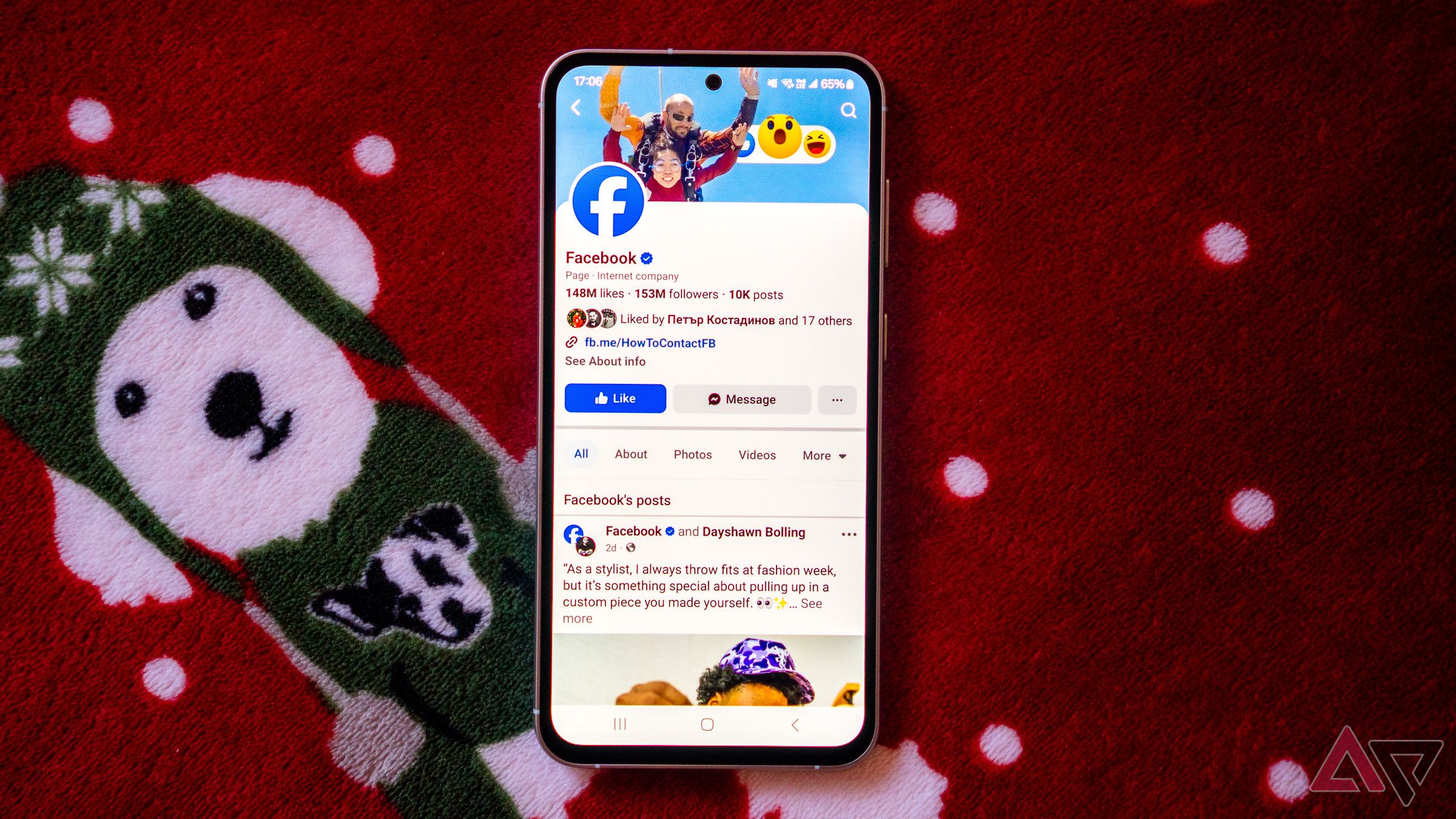 a phone displaying the facebook page of facebook on a red blanket with a picture of a dog