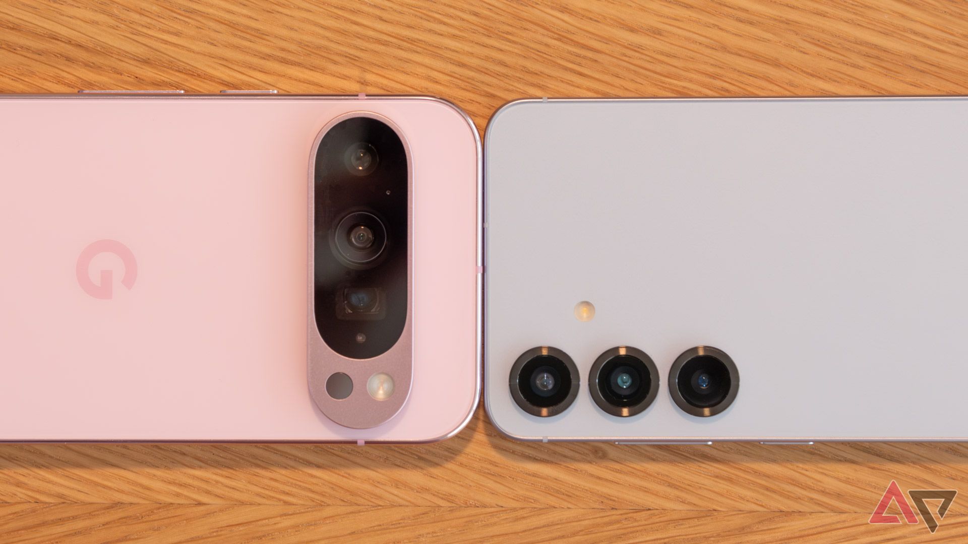A pink Pixel 9 Pro next to a blue Samsung Galaxy S25, face down on a table